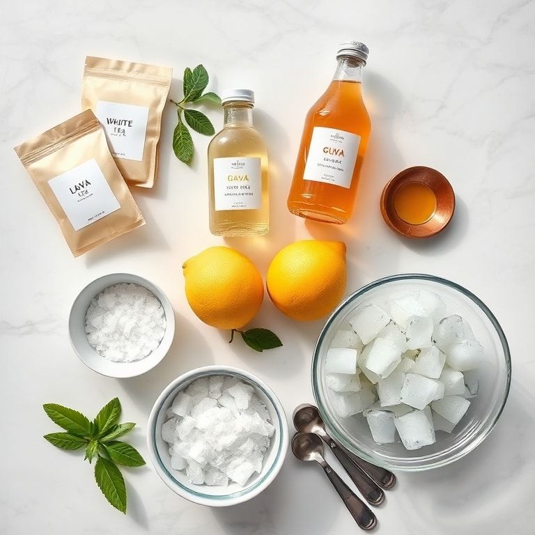Raw ingredients including guava juice, white tea bags, lemons, sugar, and ice on a marble surface