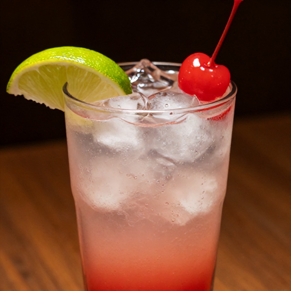 Cherry Limeade in a glass with ice, a lime wedge, and a cherry on top
