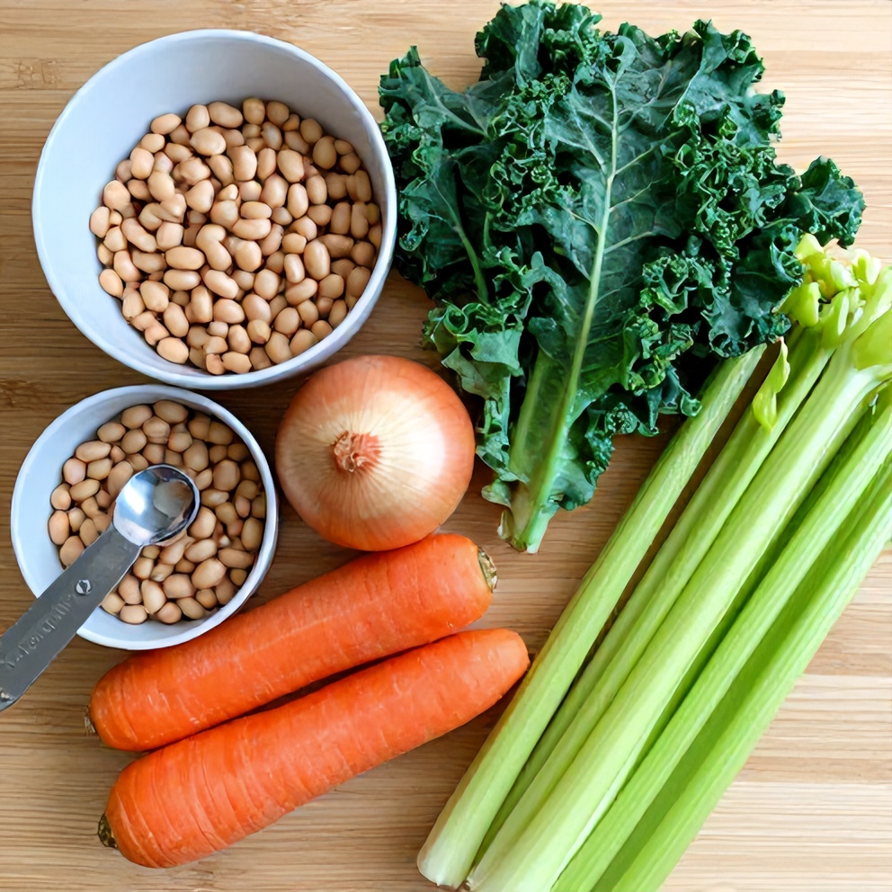 Ingredients for white bean and kale soup on a wooden surface